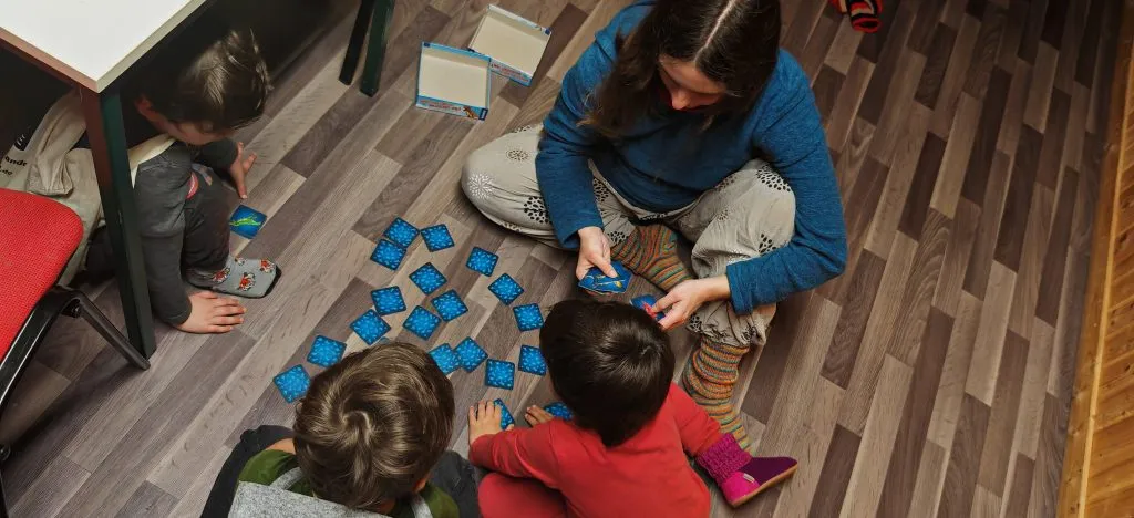 Kinder und eine Erwachsene spielen gemeinsam ein Kartenspiel